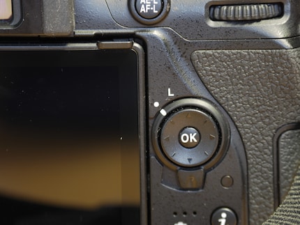 The lock switch and the four direction buttons of a Nikon SLR camera.