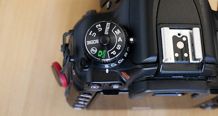 In questa fotocamera, la modalità può essere cambiata premendo il pulsante in mezzo alla ghiera.
