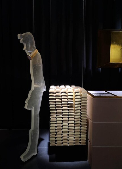Die linke Figur stellt ein Menschenleben dar, die Barren rechts stehen für 3 Tonnen Gold. Nathalie Benz, 2019