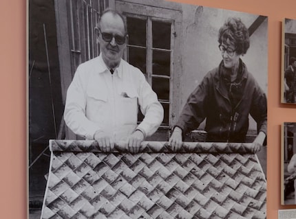 Trix und Robert Haussmann um 1982 mit einer Mira-X-Stoffrolle, deren Druck wie eine Fliesenwand wirkt.
