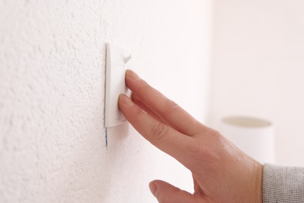Ensuite, je place les bandes adhésives sur le mur en appuyant dessus.