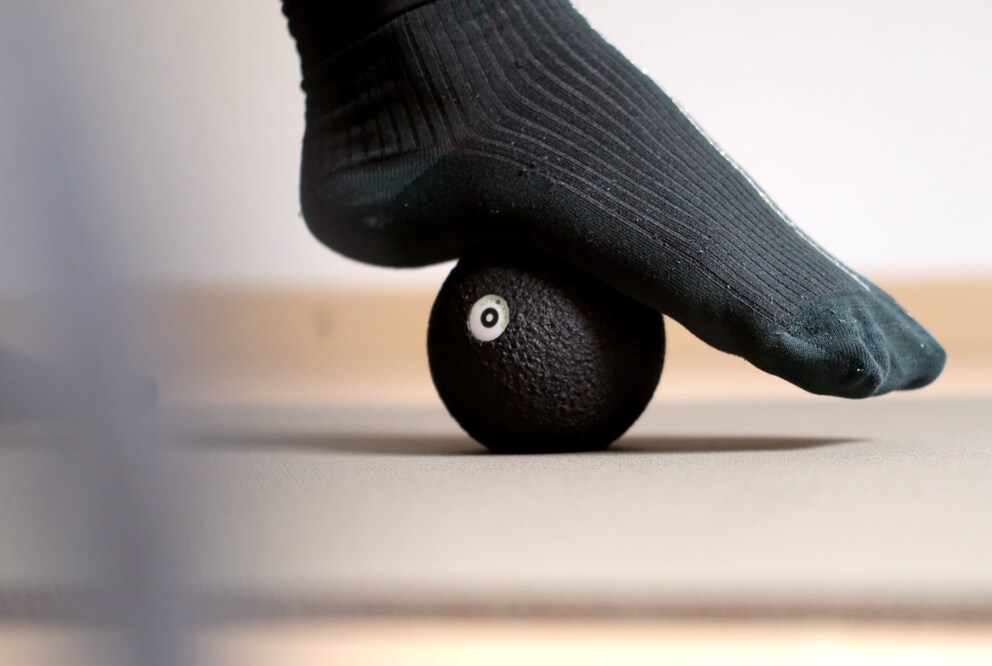 Mit einem sanften Druck wird der Fuss über dem Massageball ausgerollt.
