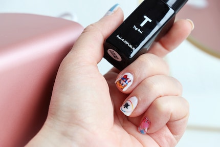 Le top coat enveloppe les ongles d'une belle brillance et scelle le dessin.