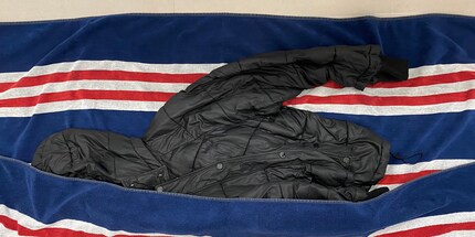 Ins Tuch einrollen und das Wasser auspressen: So trocknet die Daunenjacke schneller.