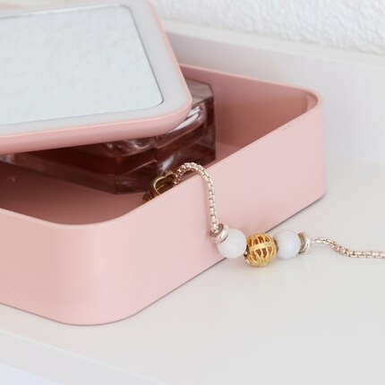 Dans la trousse de beauté, je peux ranger de petits objets comme des bijoux.