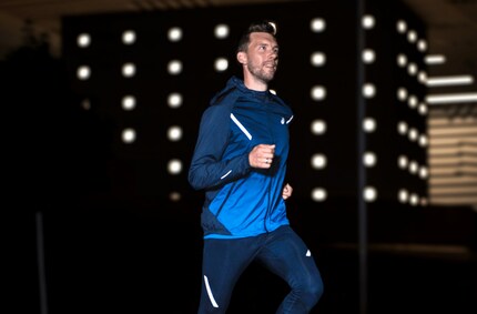 Der Asics-Modell-Athlet zeigt, wie die Streifen das Licht reflektieren. Hier trägt der Mann eine Jacke aus der gleichen Serie.