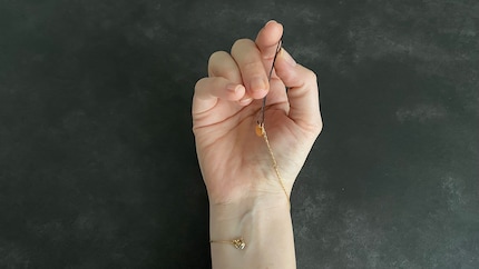 Enfilez l'épingle à cheveux dans l'œillet et ne la lâchez plus. Ainsi, vous pouvez fermer le fermoir « à deux mains ».