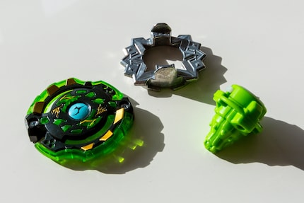 I tre componenti di un Beyblade: anello d'attacco, disco del peso e base di lama.
