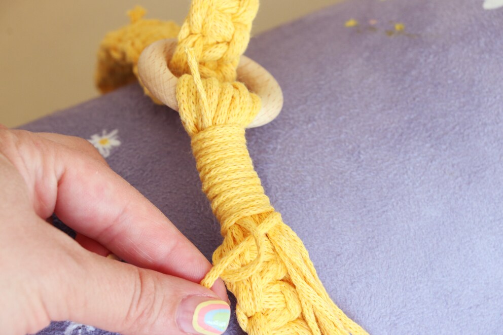 Pull the protruding tip at the top and the loop at the bottom disappears.