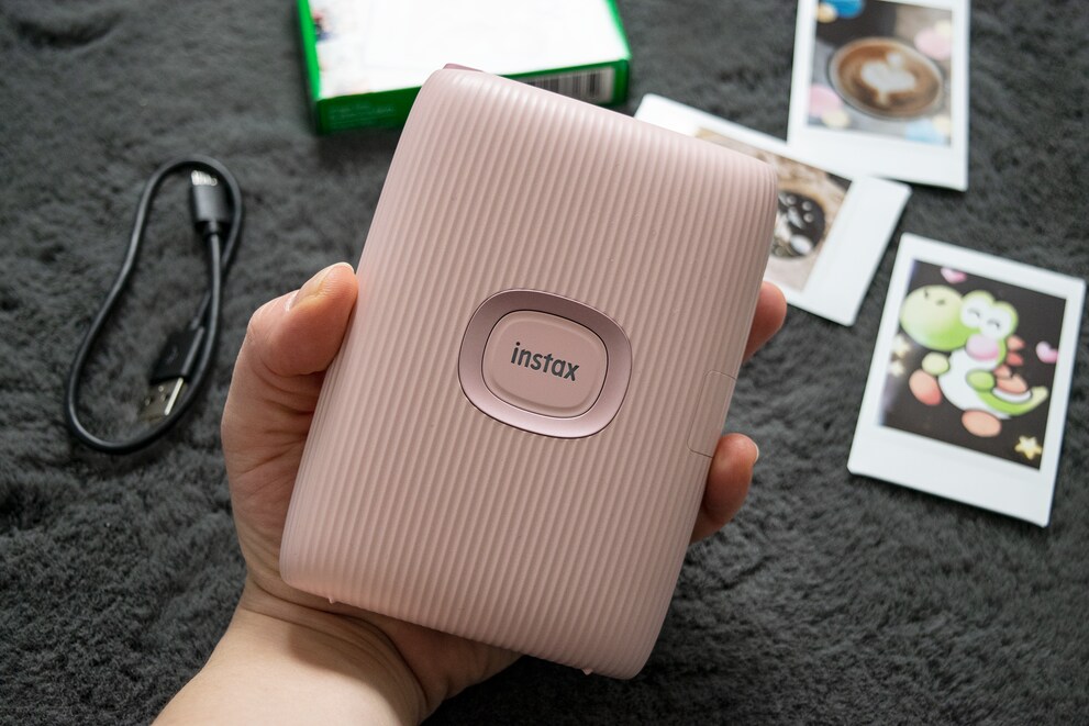 Die Instax passt gut in meine Hand und hat vorne einen grossen Einschaltknopf.