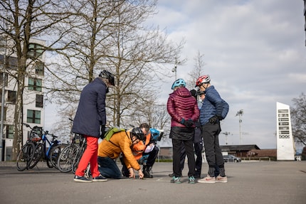 Theorie mit Kreide und einem Leuchtmarker als Velo: Kursteilnehmende diskutieren das korrekte Linksabbiegen.