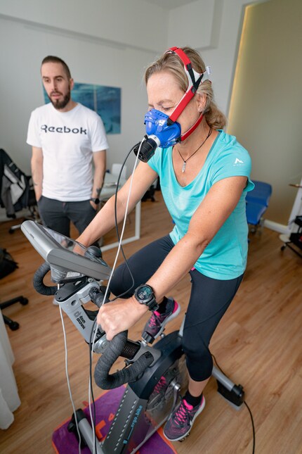 Indossando una maschera di gomma e scarpe da ginnastica, pedalo durante la spiroergometria.