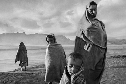 Des réfugiés enveloppés dans des couvertures attendent devant un camp à Korem, en Éthiopie, en 1984.