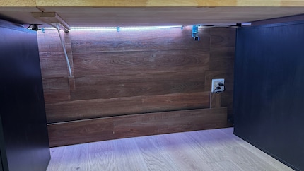 Ray cache les nombreux câbles derrière des lattes de bois sous le bureau.