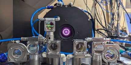  Le laser se trouve au centre de l'image ; des lentilles et des miroirs montés devant lui réfléchissent le faisceau laser et le redirigent.