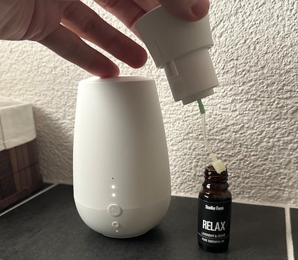La tête de pulvérisation est munie d’un tuyau que je plonge dans le flacon d’huile parfumée.