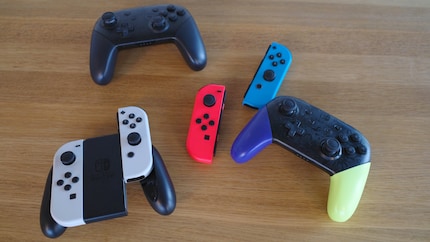 Joy-Cons in der Halterung (unten links), lose Joy-Cons (mitte) und zwei Pro-Controller (oben links und unten rechts).