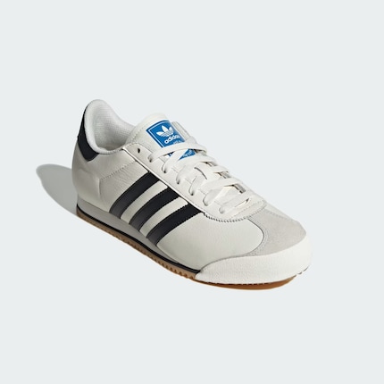 L’Adidas K 74 en blanc classique avec des bandes noires.