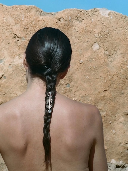Il marchio di gioielli Alighieri inserisce una spilla tra i capelli intrecciati.