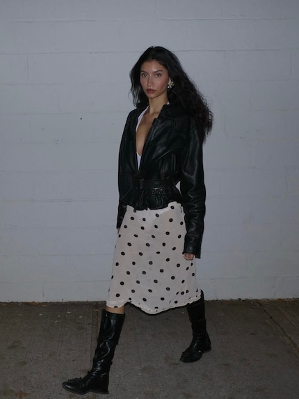 Gonna a pois femminile con una robusta giacca di pelle: una bella pausa di stile.