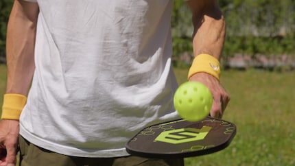 La parte pickleball del gioco: una racchetta di legno, una palla di plastica.